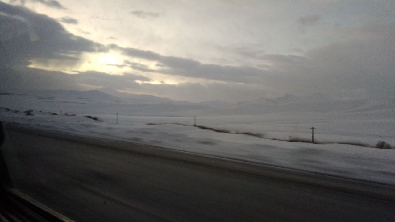 Snow-covered plain and mountains at dawn, seen from the car