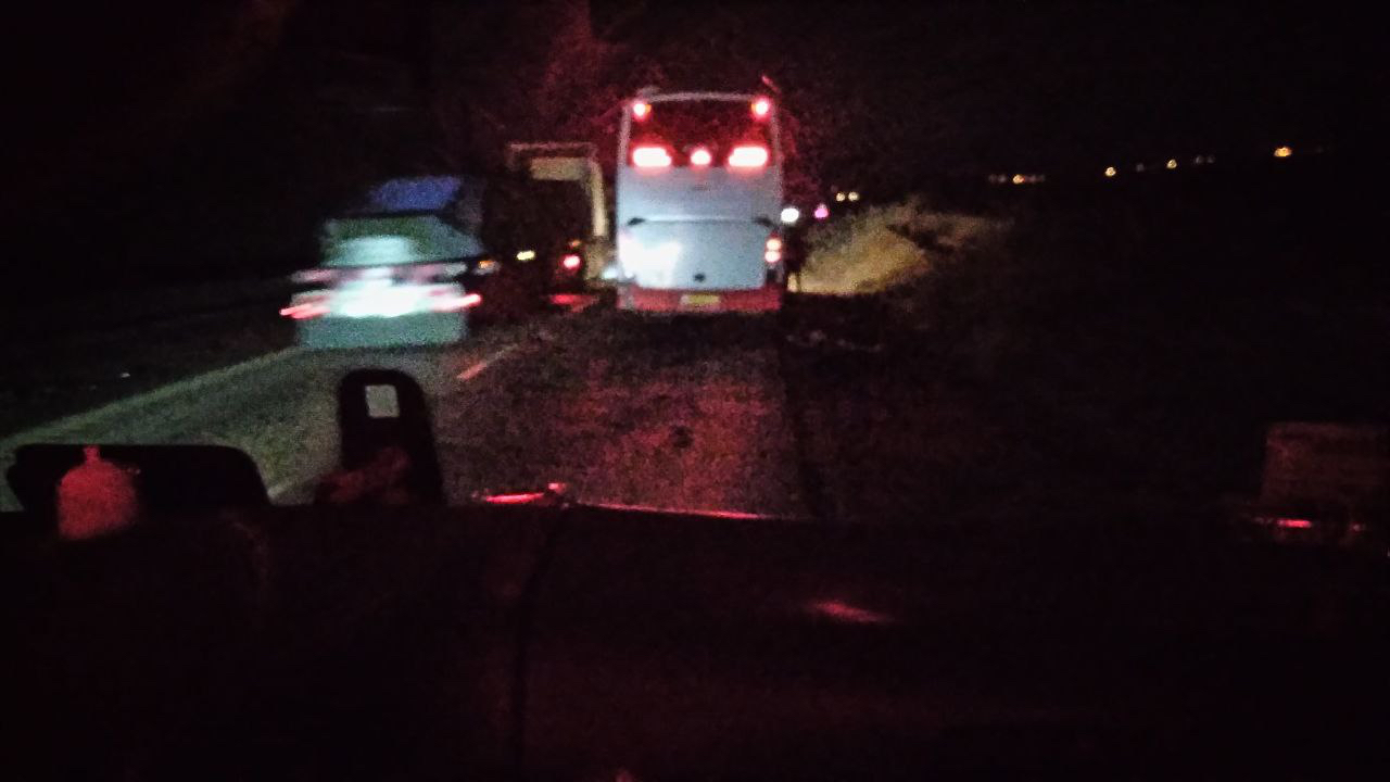 The bus stopped on the shoulder at night, hazard lights on