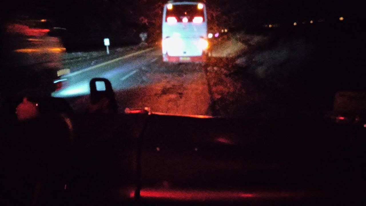 Another vehicle passing the stopped bus in the dark